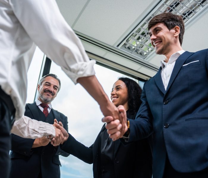 Caucasian businessman making a handshake together while stand in office. Attractive team of employee worker enjoy partnership agreement after negotiations for business deal during working in corporate